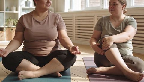 Plus-size women practicing seated meditation together in bright yoga studio