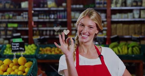 Smiling produce clerk holding ok gesture in grocery fruit section