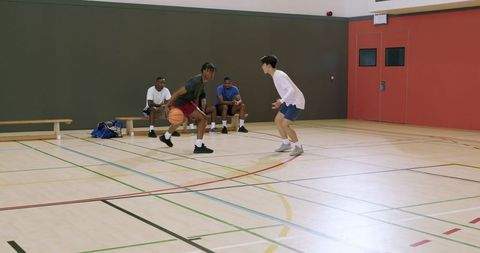 Dynamic indoor basketball drill: african american player driving baseline defender guarding