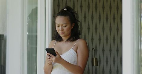 Young woman enjoying casual conversation on smartphone indoors