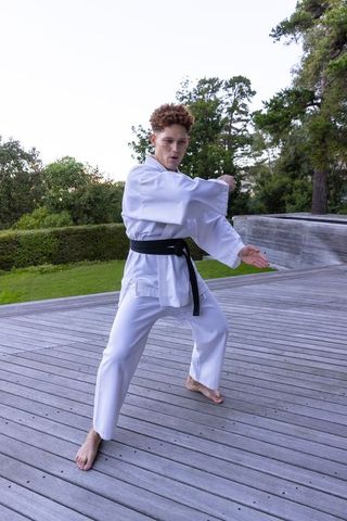 Male martial artist posing outdoors in white gi and black belt