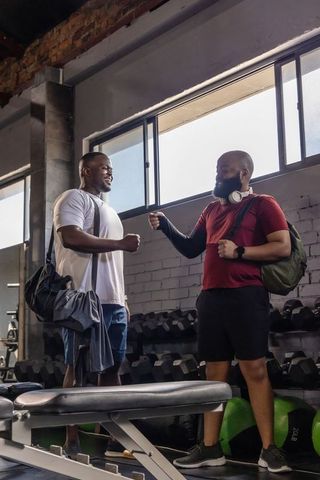 Two african men fist-bumping in urban gym post-workout conveying camaraderie and fitness motivation