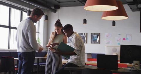 Coworkers collaborating with binder and tablet in modern office