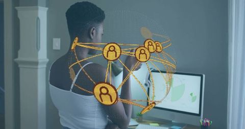 Woman standing at home office viewing gold holographic network visualization on monitor