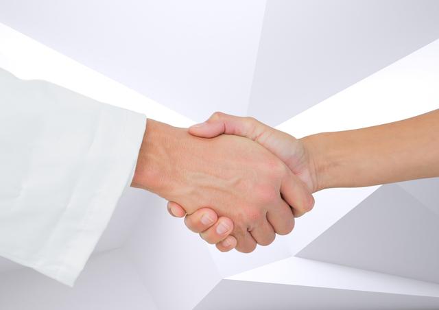 Close-up shot depicting a handshake between a doctor and a patient in a bright, modern environment. Useful for illustrating themes of healthcare, partnership, trust, medical services, patient care, professional relationships, and support.