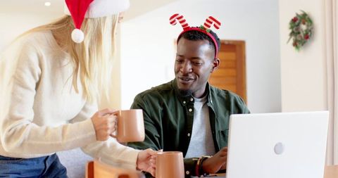 Festive Couple Sharing Hot Drinks and Laughter in Cozy Home