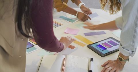 Creative team collaborating over color swatches and tablet for branding and UI design