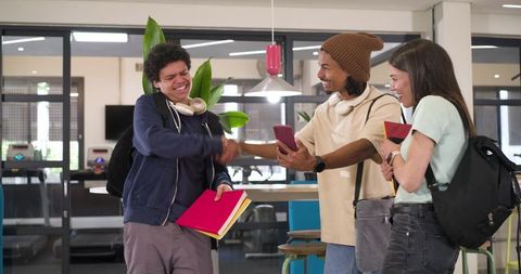 College students greeting and sharing smartphone in modern campus study lounge