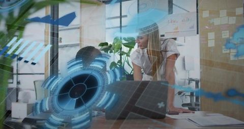 Women collaborating over laptop with futuristic holographic interface in modern office