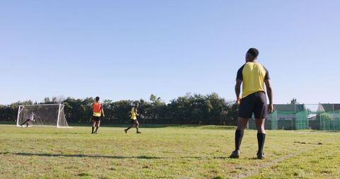 Diverse male athletes practicing soccer skills on green field