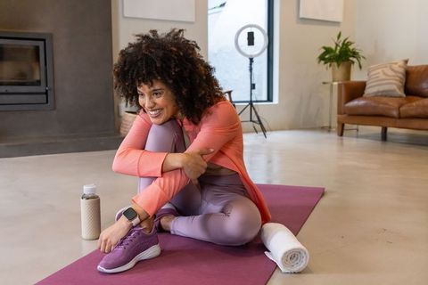 African american woman recording home workout on purple yoga mat with ring light