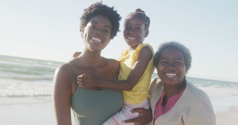 Three Generations Smiling by the Ocean on a Sunny Day