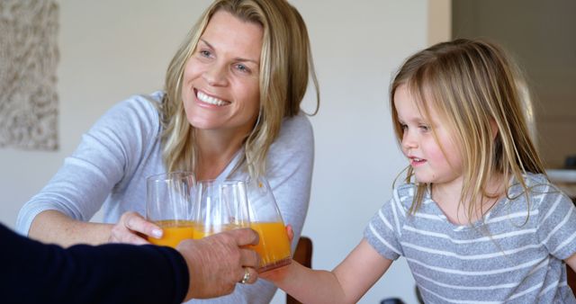 Smiling family toasting with orange juice in living room - Download Free Stock Images Pikwizard.com