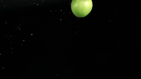 Green Apple Rotating in Slow Motion Against Black