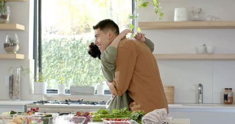 Couple Embracing in Modern Kitchen Preparing Fresh Vegetables