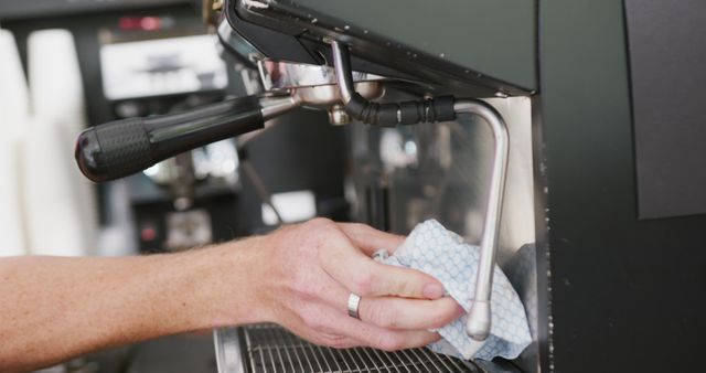 Hands of caucasian male barista cleaning coffee machine with cloth in cafe. Local business owner and hospitality concept.