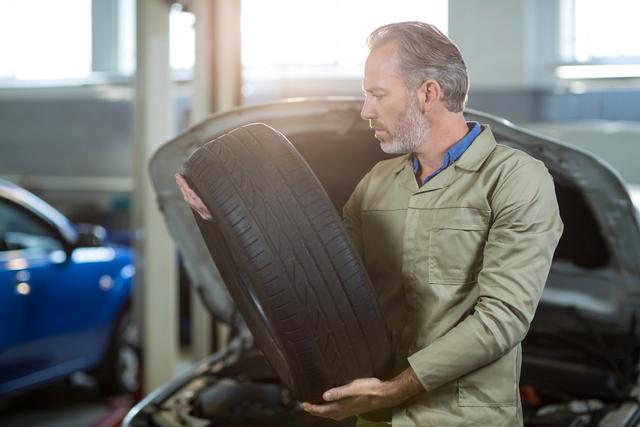Mechanic holding a tyre in repair shop