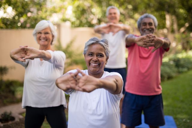 Group of senior individuals stretching arms and exercising outdoors in a garden. Ideal for promoting healthy lifestyles, senior fitness programs, community activities, and wellness campaigns.