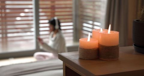Relaxed Asian Woman Enjoying Cozy Moment With Candles and Music