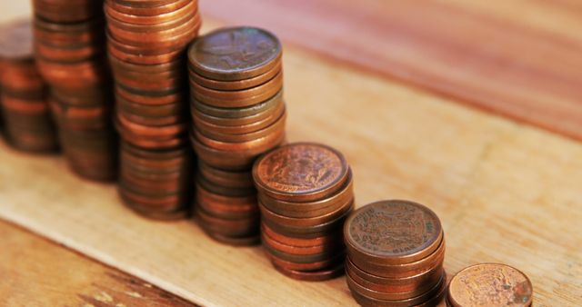 Rows of copper coins increasing in height placed on a wooden surface indicating financial growth or savings. Ideal for illustrating concepts of economic progress, budgeting, and investment. Useful for financial blogs, educational materials, and money management visuals.