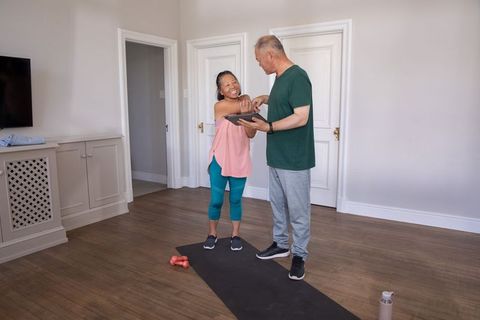 Asian senior couple exercising at home using tablet for guided fitness and stretching routine