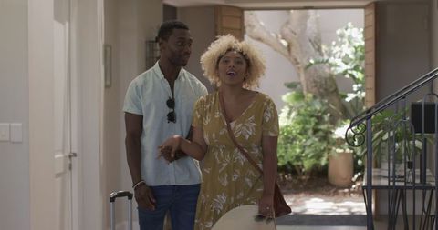 Happy Couple Entering Bright Home Doorway on Vacation Day