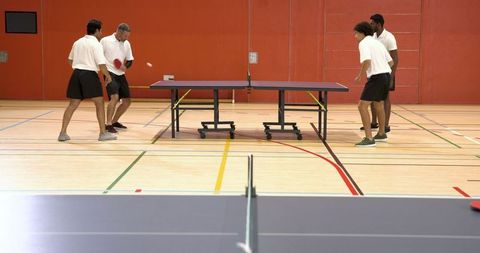 Diverse Group Playing Table Tennis in Gym Setting
