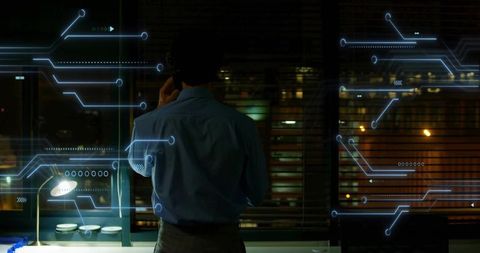 Executive standing by office window holding smartphone with holographic circuit interface