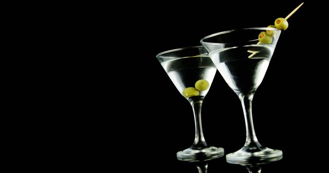 Two martini glasses with olives on a dark background, creating an elegant and sophisticated presentation. The image evokes a sense of luxury and celebration, often associated with cocktail parties and special occasions.