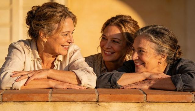 Three women sharing sunset laughter on terracotta balcony sunlit embracing warm friendship