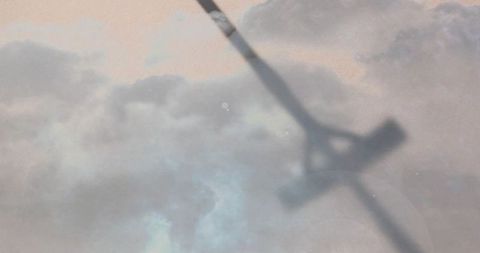 Diagonal aircraft silhouette crossing pastel cloudscape at dawn