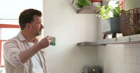 Senior man enjoying morning coffee near sunlit kitchen