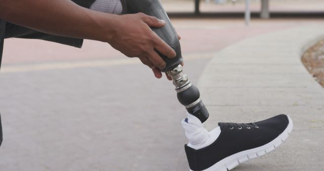 Close up of biracial man checking his prosthetic leg in city. Sport, active lifestyle and disability.