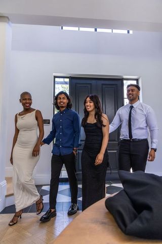 Diverse friends arriving in elegant evening attire walking through modern foyer entrance