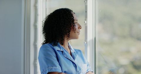 African American Clinician in Light Blue Scrubs Gazing Out Clinic Window Reflective Portrait