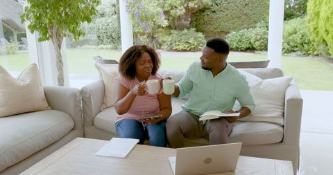 Couple planning finances with laptop and documents on cozy sofa