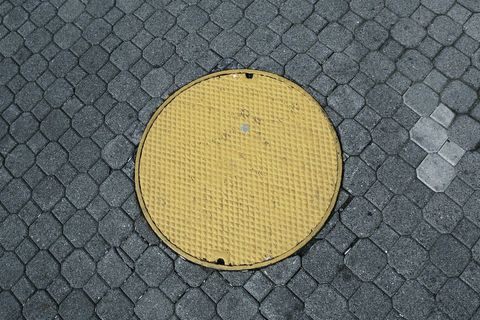 Yellow Manhole Cover on Cobblestone Street