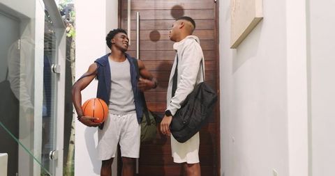 Friends Conversing in Entryway Holding Basketball and Bag