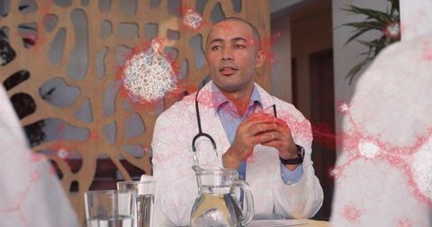 Doctor leading clinical team discussion at table with stethoscope and water pitcher