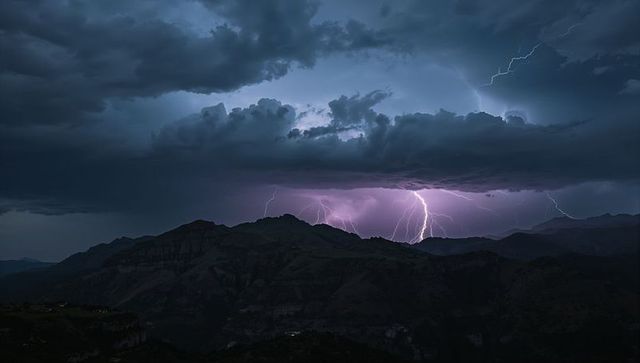 Forked lightning striking mountain ridge at night with dramatic storm clouds and purple sky