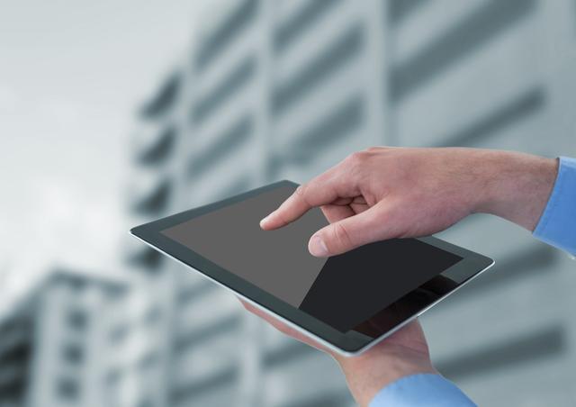 Digital composite of Hands with tablet against blurry building