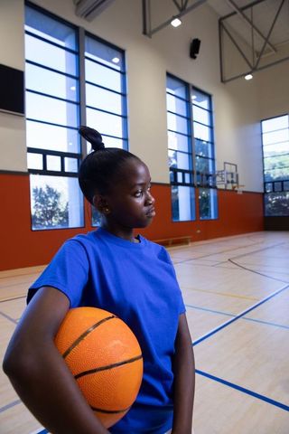 Young Athletic Girl Holding Basketball in Indoor Court