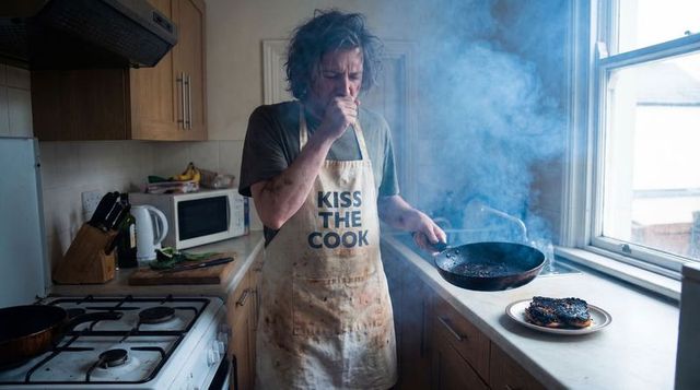 Frustrated home cook coughing over smoking pan with burnt toast and cluttered kitchen