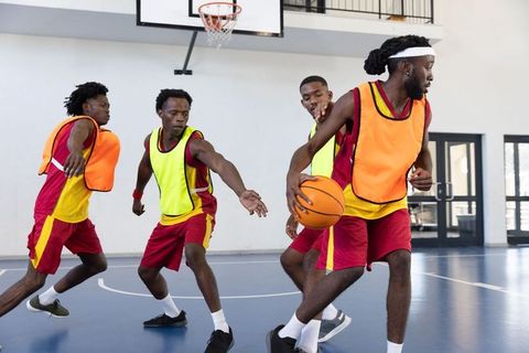 Players in Action on Basketball Court Wearing Colorful Vests