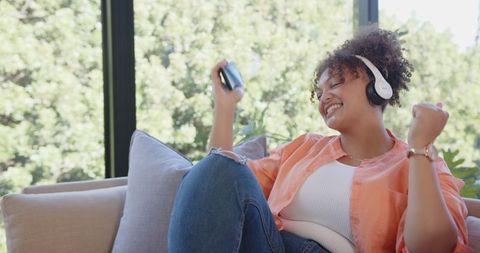 Cheerful Woman Enjoying Music Relaxing on Sofa