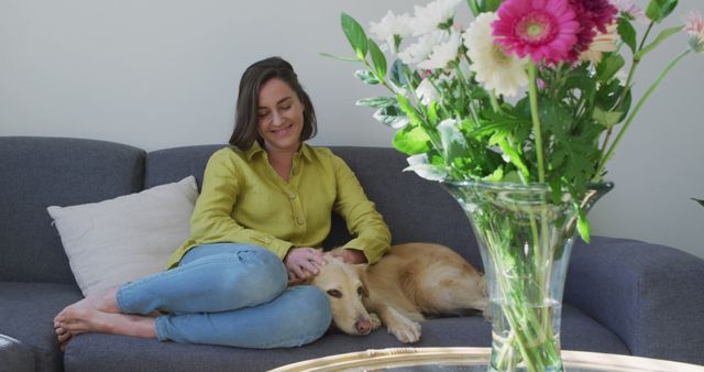 Caucasian woman smiling and sitting on couch with dog - Download Free Stock Photos Pikwizard.com