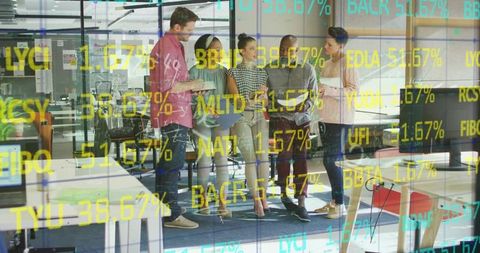 Collaborating team analyzing market ticker through glass wall in modern fintech office