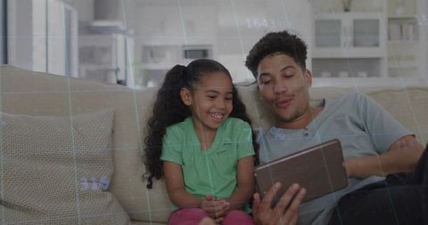 Father and daughter watching tablet on sofa, laughing and learning with digital overlay