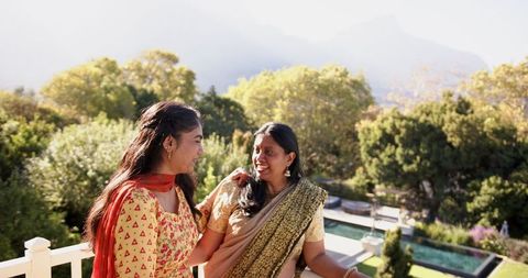 Smiling indian mother and daughter bond on scenic balcony