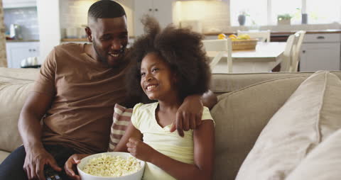 Father and Daughter Watching TV Together at Home Relaxing